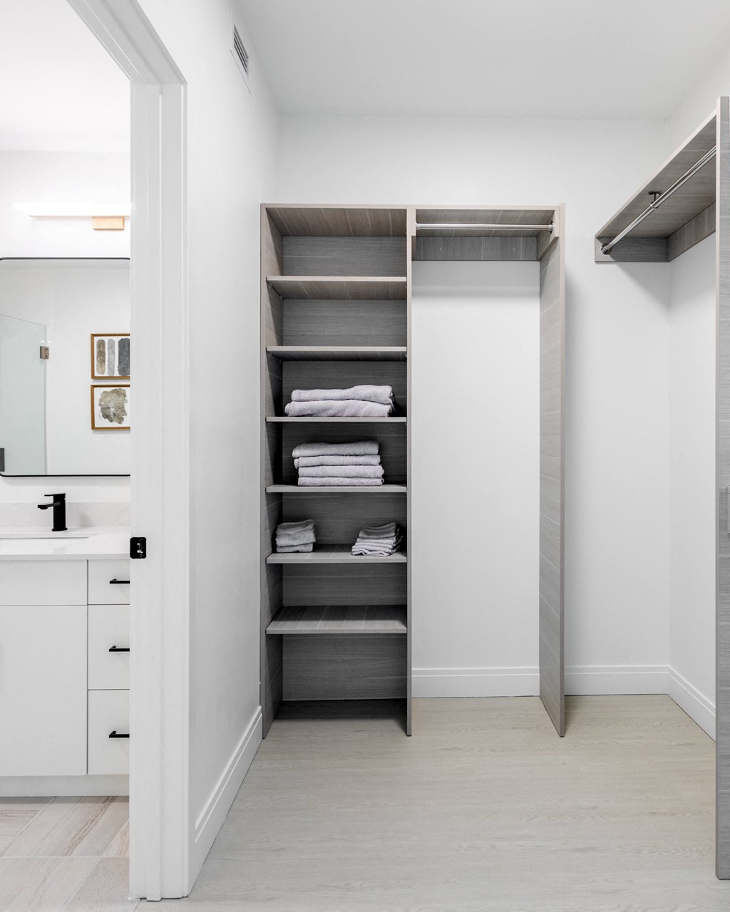 a small bathroom with a white closet with shelves and a sink