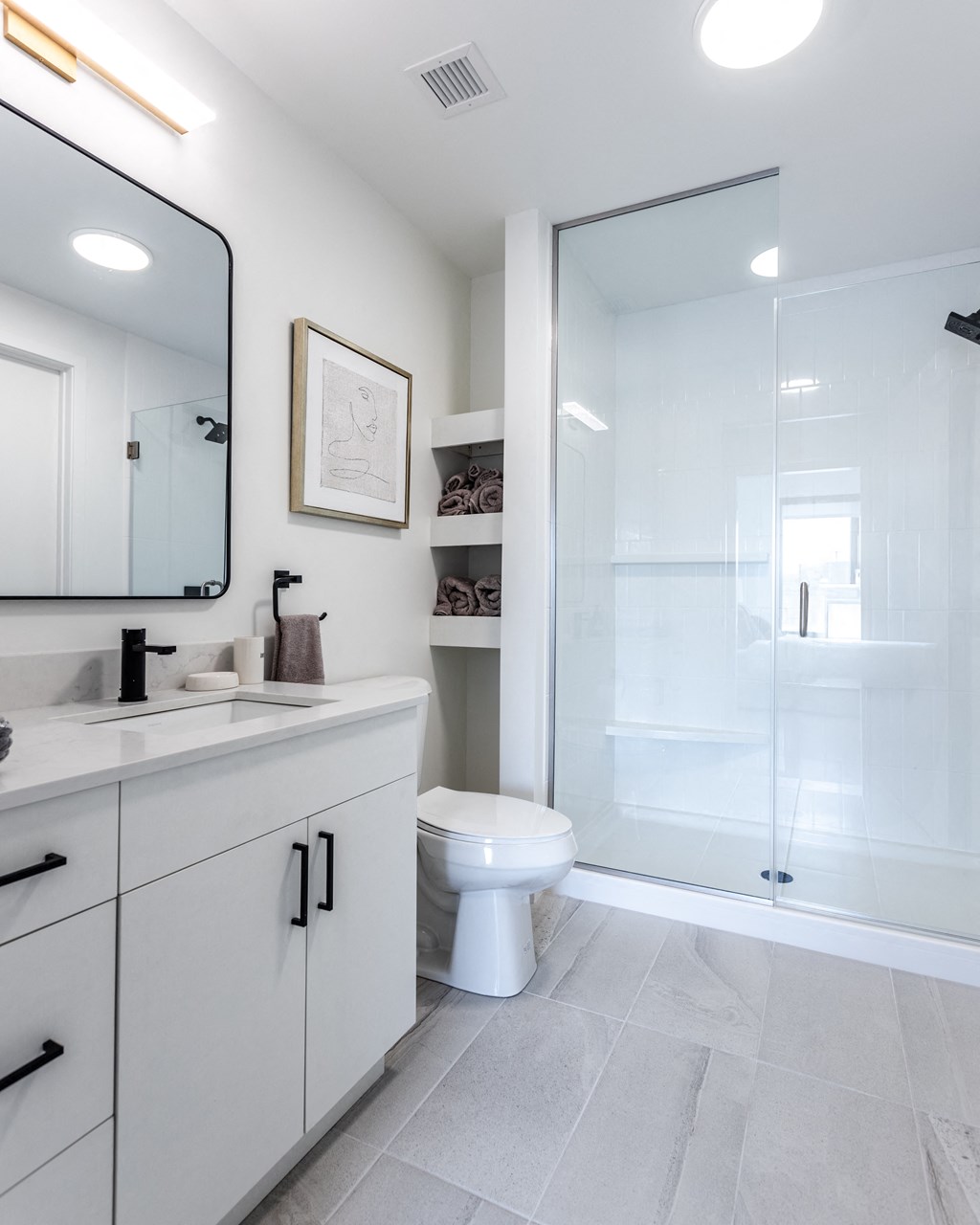 a white bathroom with a glass shower and a toilet