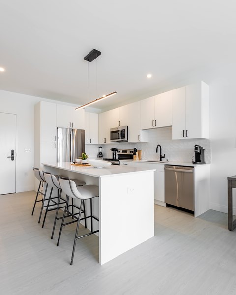 a kitchen with white cabinets and a white island with bar stools