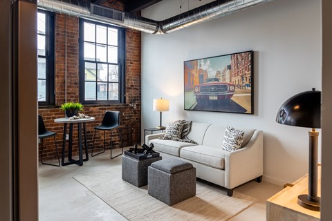 A living room with a white couch and a painting of a car on the wall.