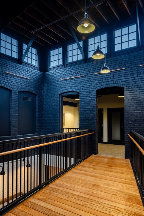 A long wooden walkway leads to a doorway in a brick building.