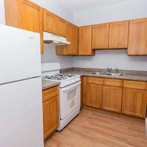 A kitchen with wooden cabinets and a white fridge.