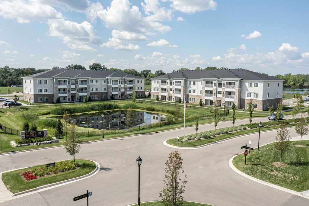 SKy view of Stone Ridge of Shelby Community. Pond in center of community, green grass and paved roads throughout.