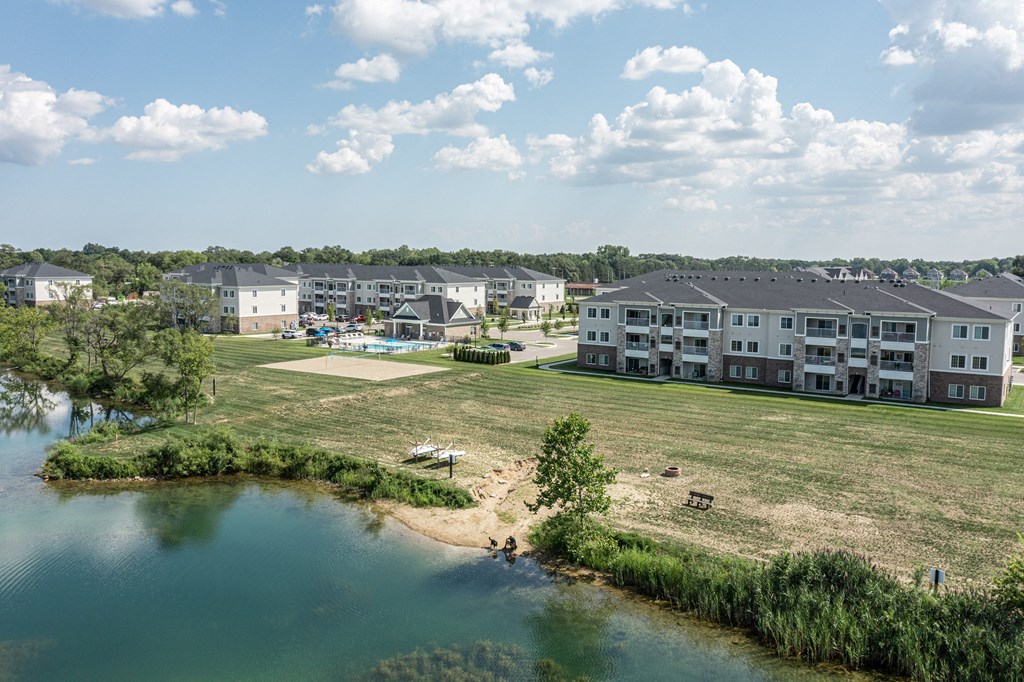 Pond view of community, kayak storage and beach area with community in background.