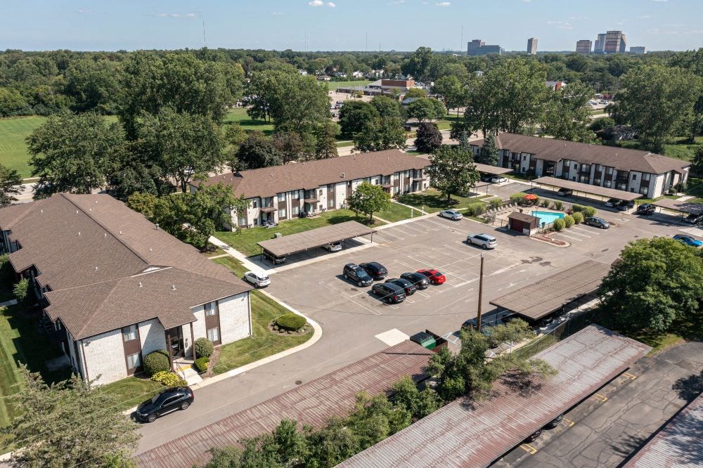 an aerial view of an apartment complex with parking lot and cars