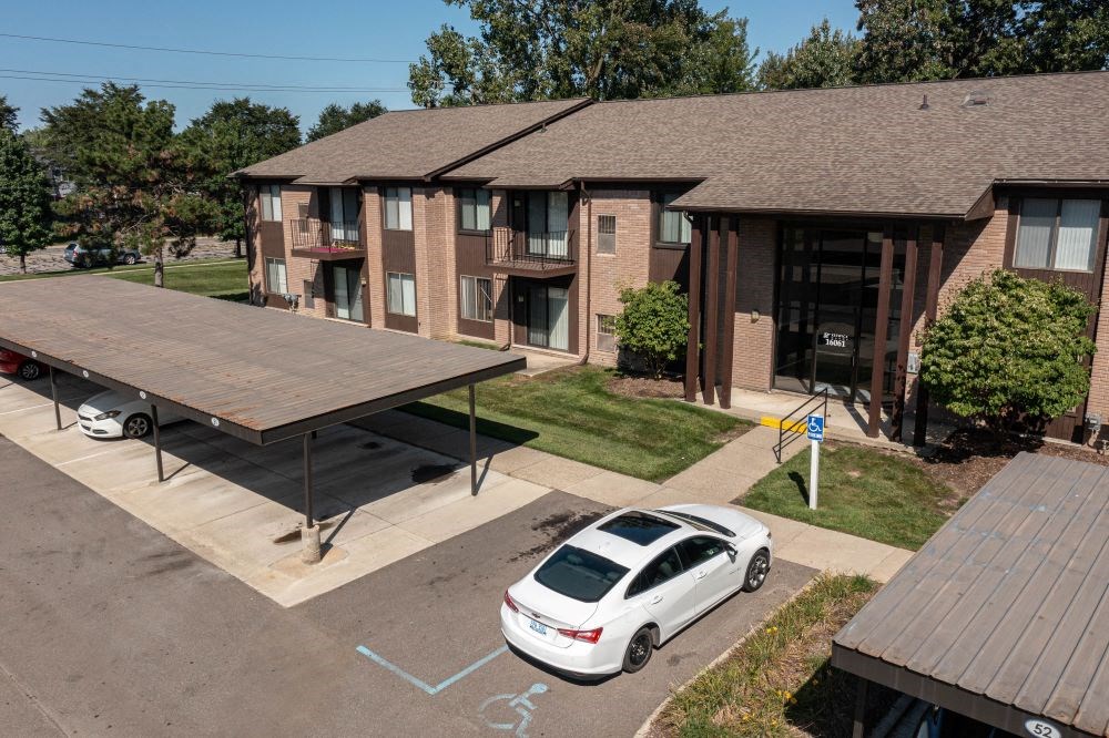 a parking lot with a white car parked in front of a brick apartment building