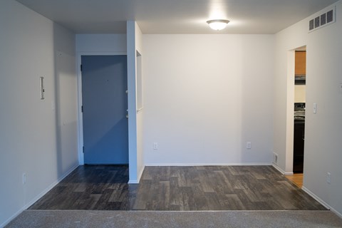 a empty living room with wood flooring and a blue door
