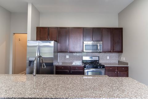 Kitchen with dark cherry cabinets, granite counter tops, and stainless steal appliances.