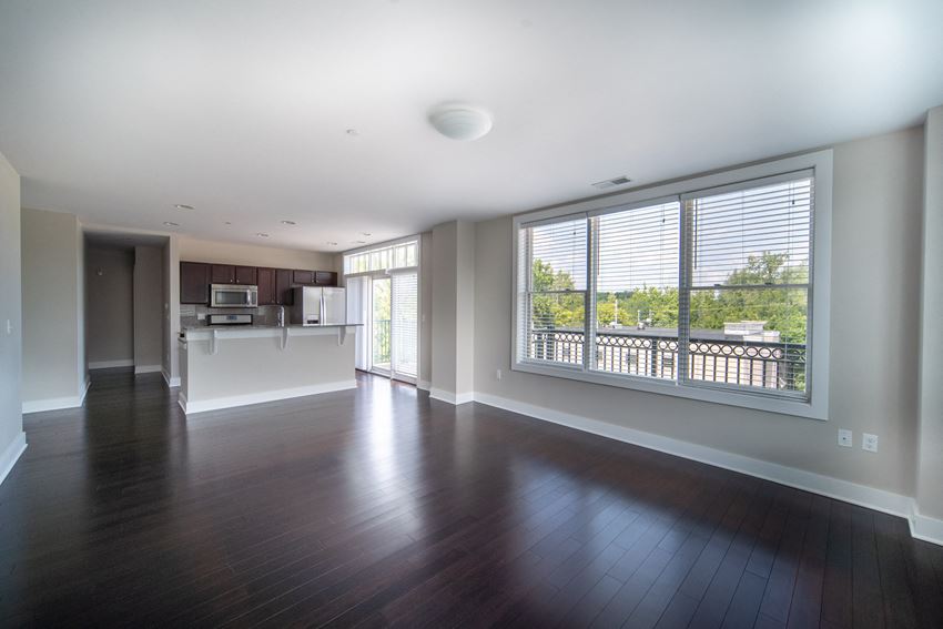 Kitchen, and living area with dark hardwood like floors and large picture windows at the Residences of Creekside. - Photo Gallery