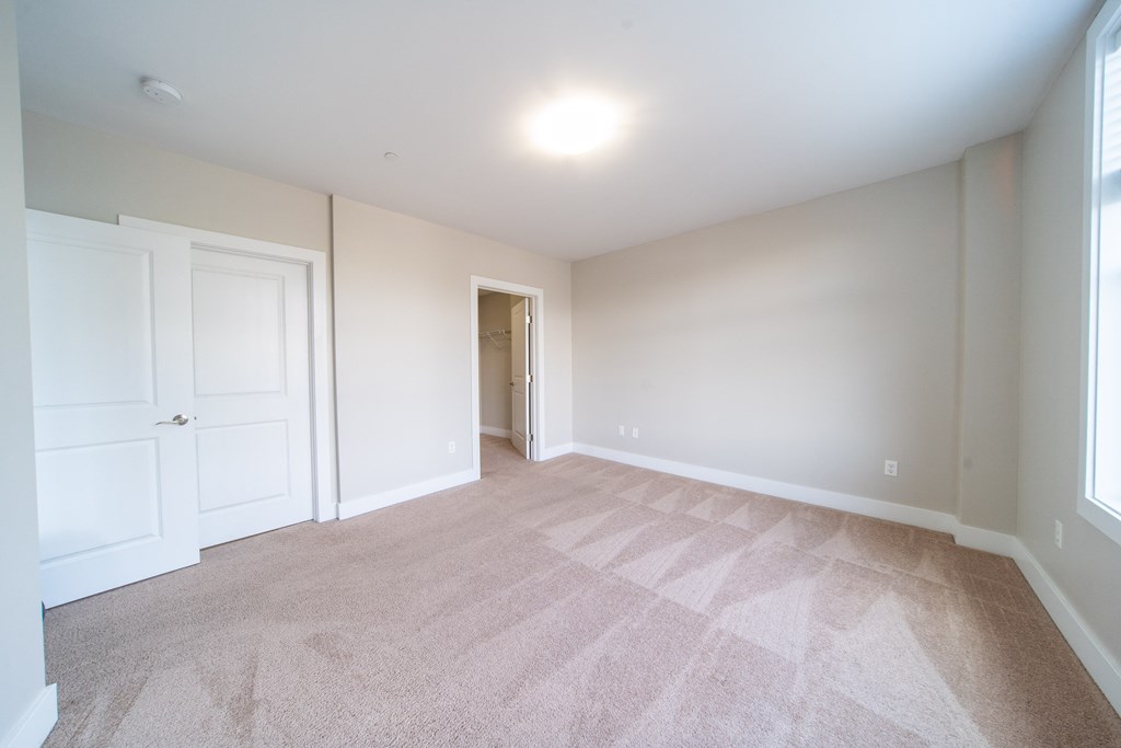 Bedroom with plush carpeting, cream  and cream walls.