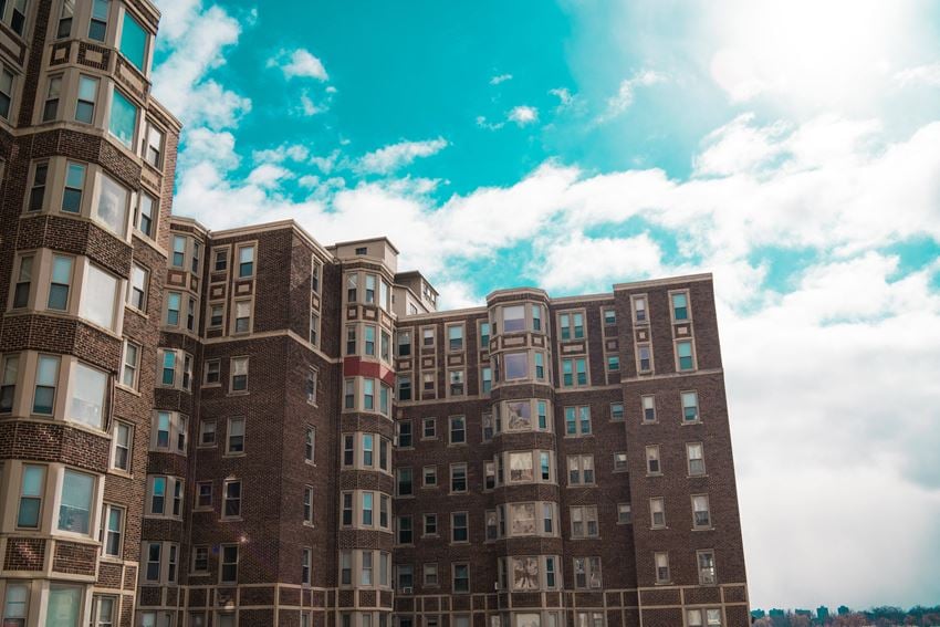 a row of brick apartment buildings against a cloudy blue sky