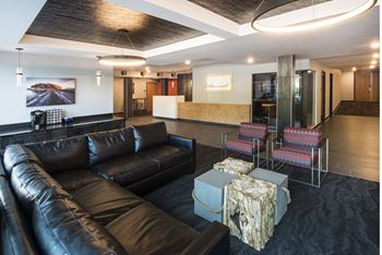 A black leather couch in a room with a wooden floor.