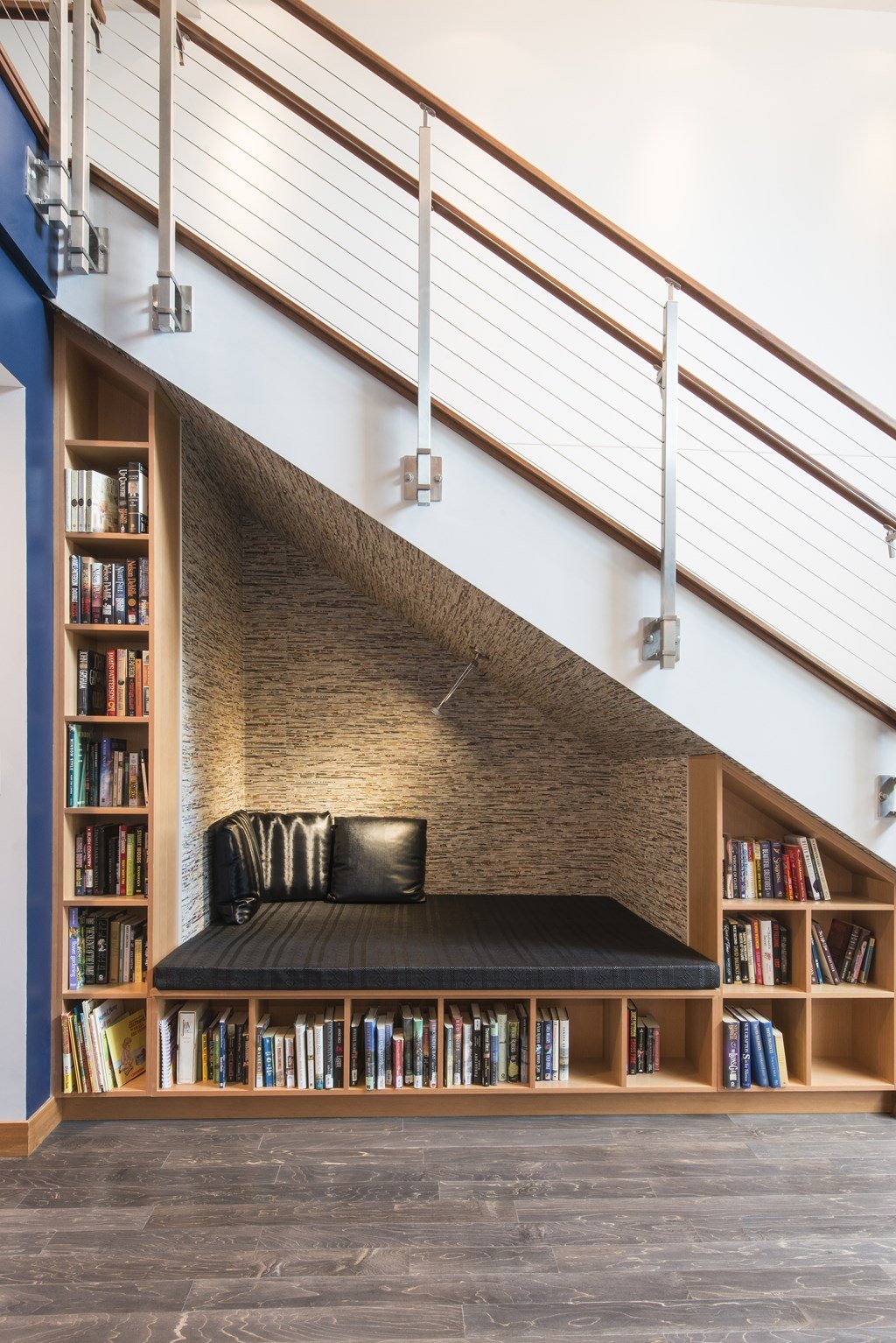 A black couch with a wooden bookshelf on the side.