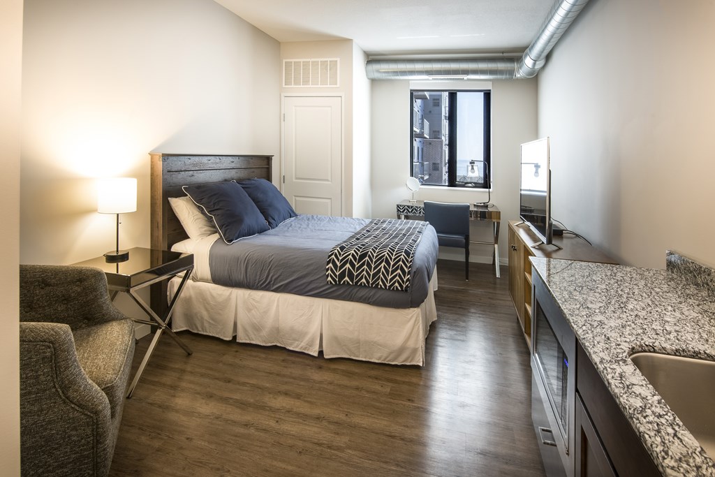 A bedroom with a bed, chair, and window.