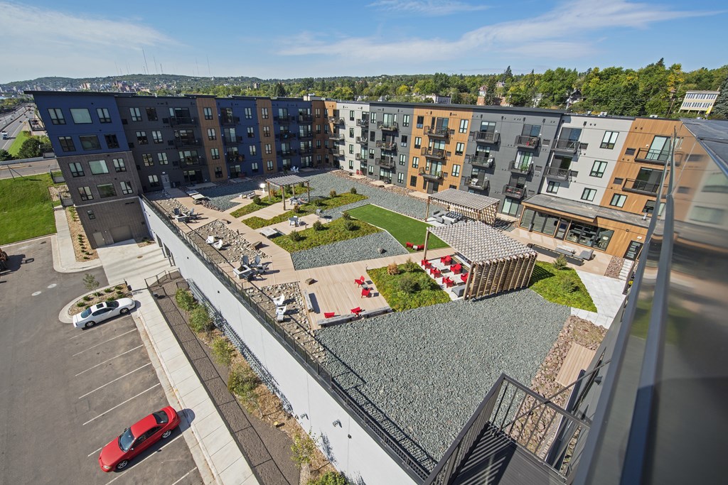 A parking lot with a red car is in front of a building.
