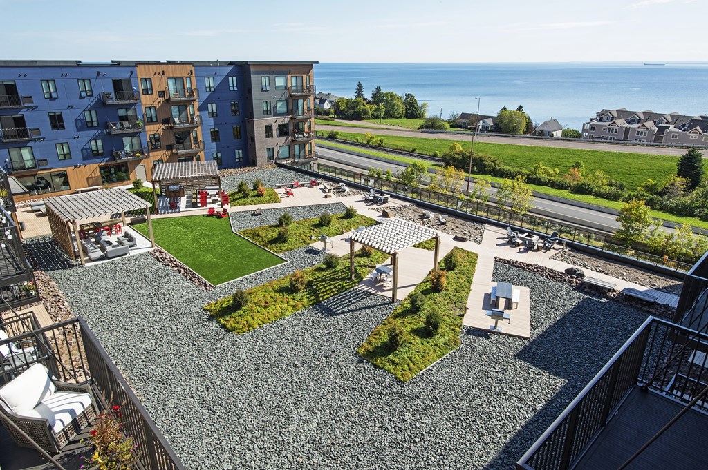 A view of a rooftop garden with a parking lot and buildings in the background.