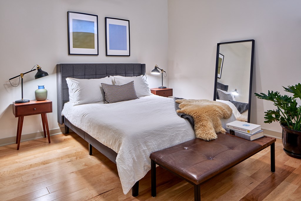 a bedroom with a large bed with white bedding and a brown leather bench at the end
