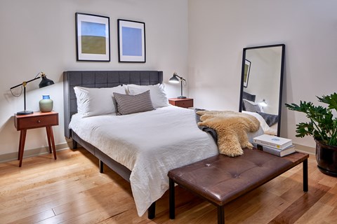 a bedroom with a large bed with white bedding and a brown leather bench at the end