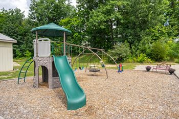 A playground with a green slide and a green canopy.