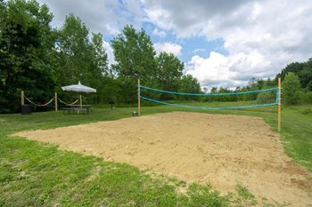 A volleyball net is set up in the middle of a sandy area.
