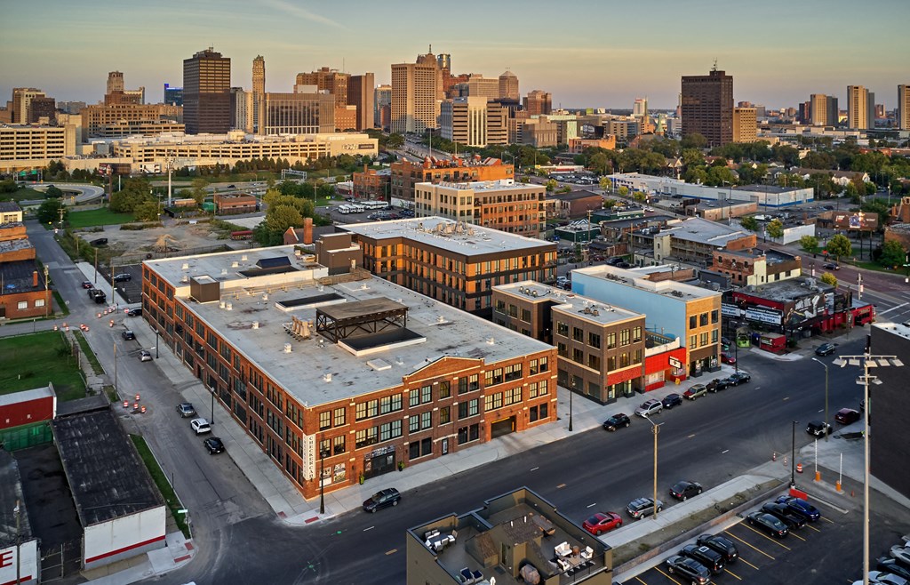 an aerial view of a large brick building with a gray roof with a city in the background