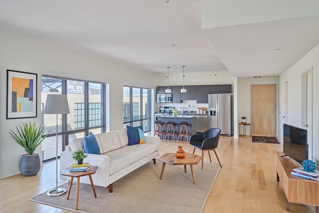 a living room with a couch and a table in front of a kitchen