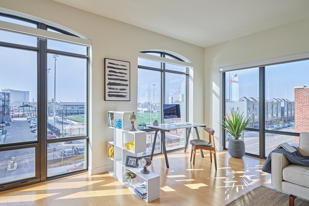 a living room with large windows and a desk with a chair
