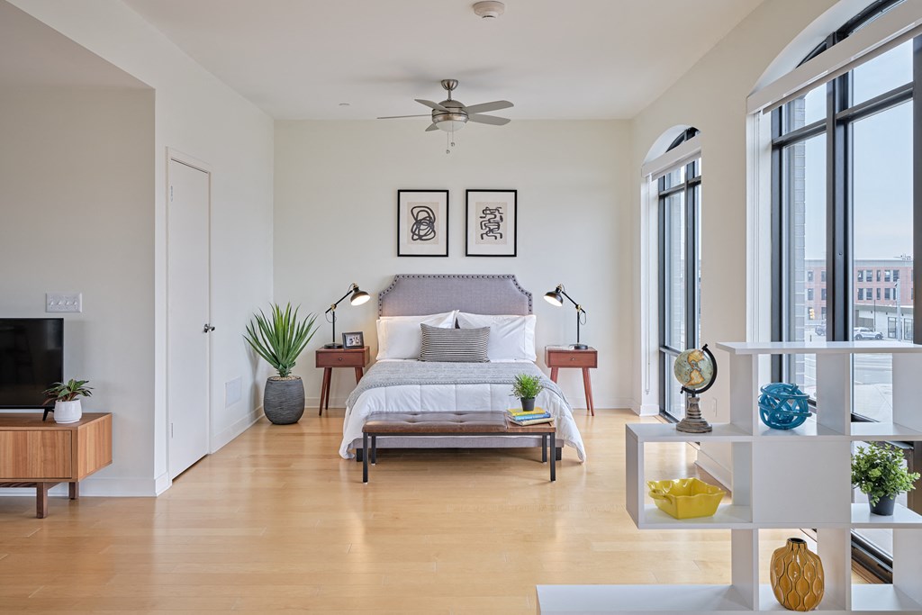 a bedroom with a bed and a ceiling fan and large windows