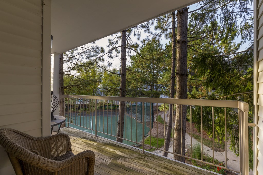 A balcony with a chair and a view of a pool and trees.