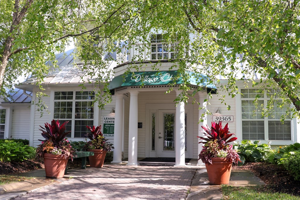 a white building with potted plants in front of it at Village Club of Farmington Hills, Farmington Hills, 48331