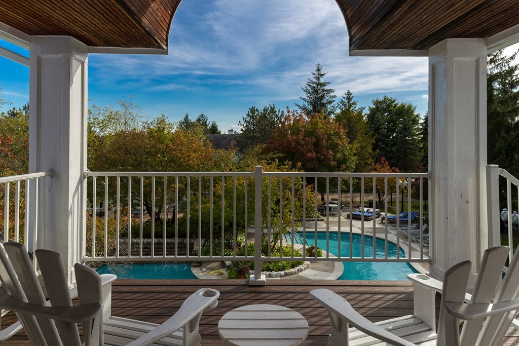 a view of a swimming pool from a porch with chairs at Village Club of Farmington Hills, Michigan, 48331