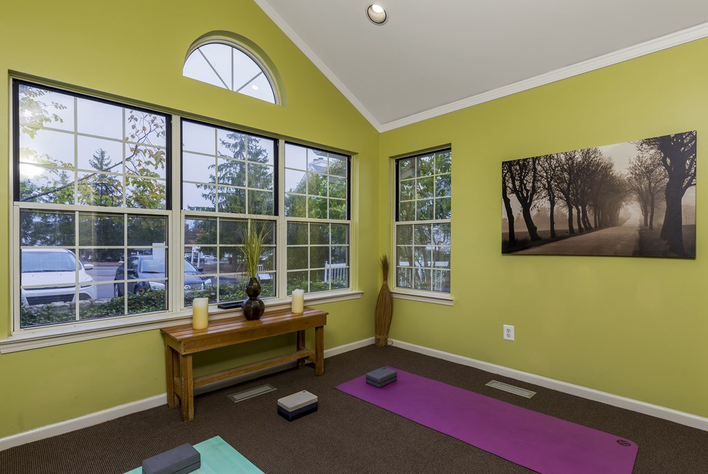 A room with a green wall and a purple yoga mat on the floor.