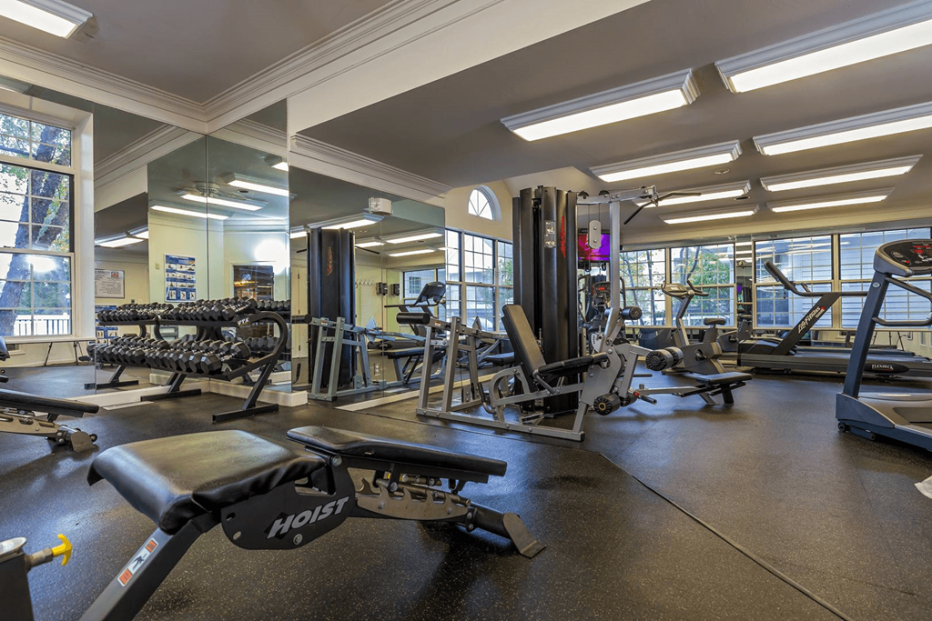 a gym with weights and other exercise equipment and windows at Village Club of Farmington Hills, Michigan, 48331