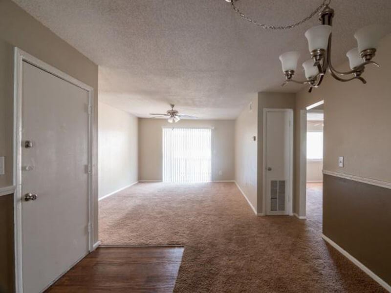 Living and dinning area with plush carpeting, and light neutral walls and a silver chandler.