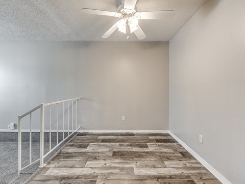 A room with a ceiling fan and wooden flooring.