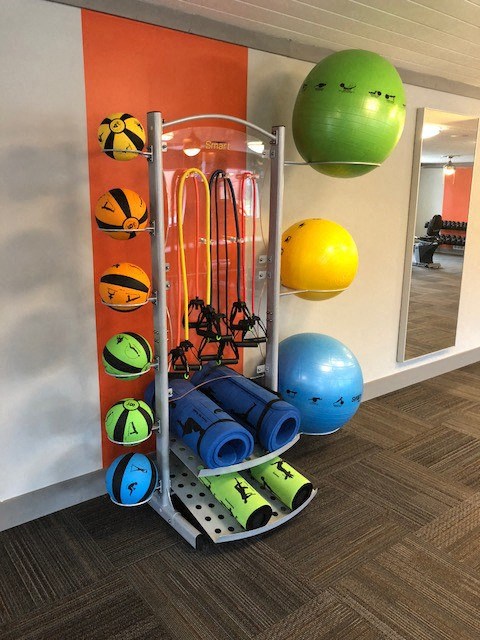 a gym with weights and balls on a rack