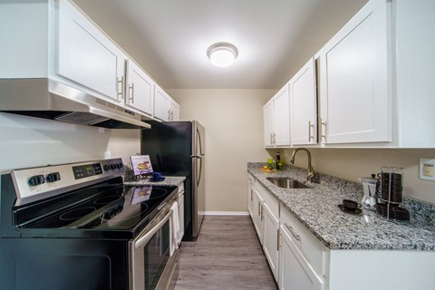 a kitchen with white cabinets and granite counter tops and black appliances