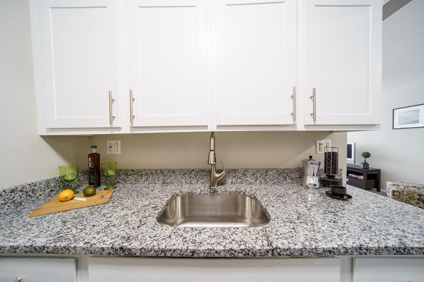 Stainless Steel Sink Stainless steel sink with white upper cabinets and grey and white stone counters. - Photo Gallery