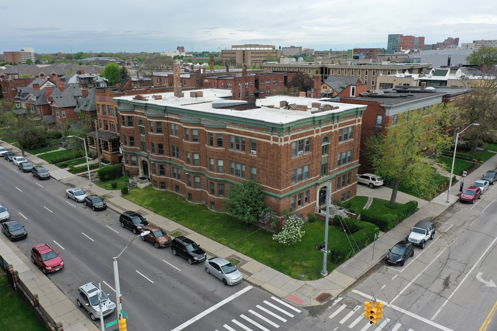 a large brick building with a green roof on a city street