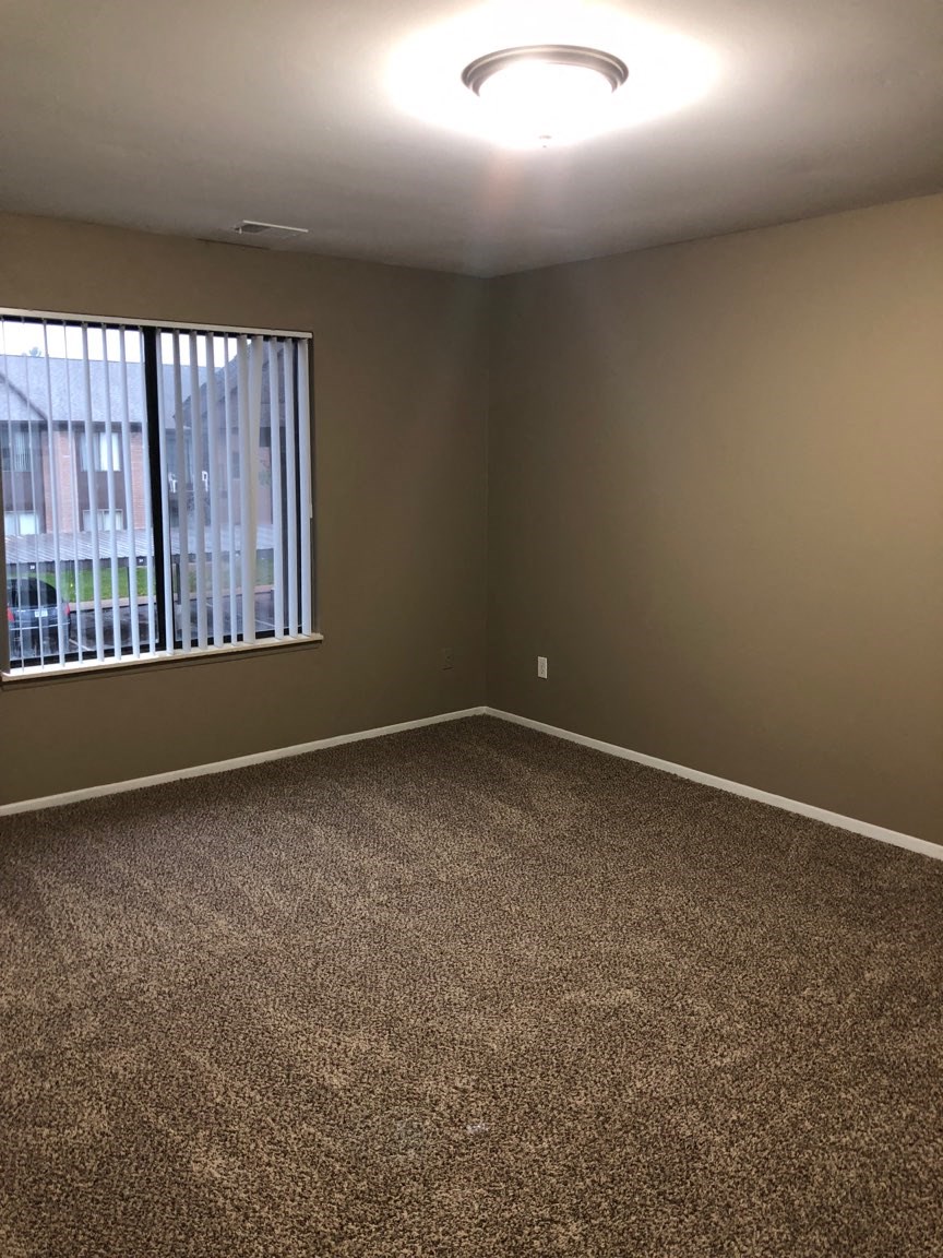 an empty room with a window and carpet
