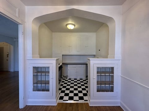 a kitchen with white cabinets and a black and white checkered floor