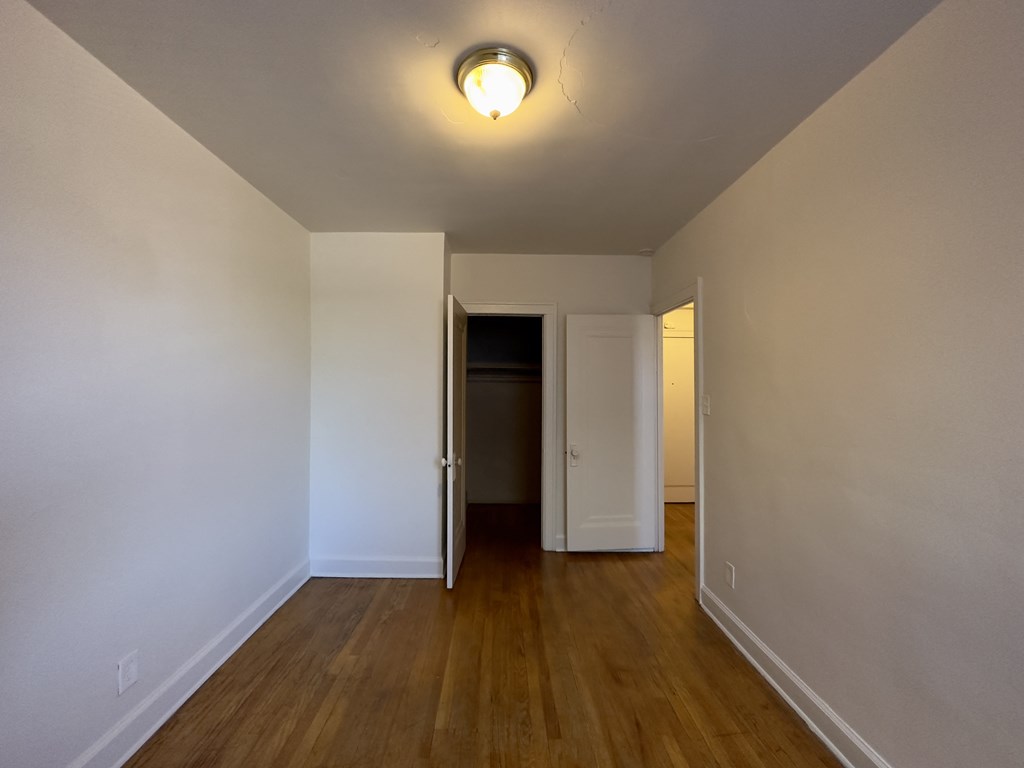 a bedroom with hardwood floors and white walls