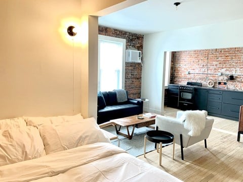 a bedroom with a bed and a living room with a brick wall