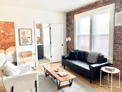 a living room with a couch and a coffee table and a brick wall