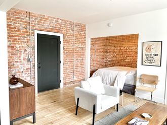 a bedroom with a bed and a brick wall     and a chair