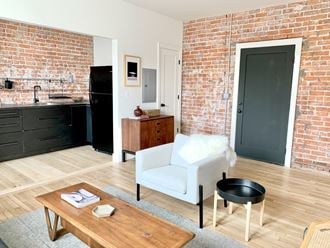 a view of a living room and a kitchen with a brick wall