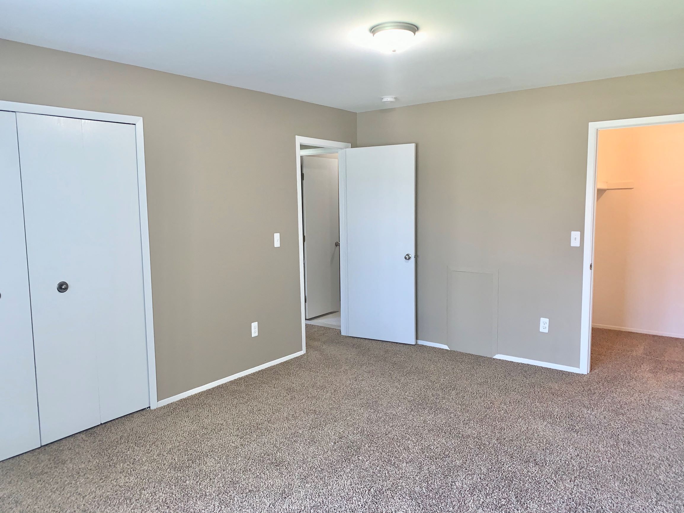 an empty room with two doors and a carpeted floor