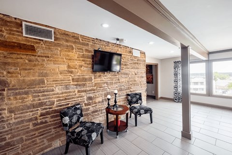 A living room with a brick wall and a television mounted on it.
