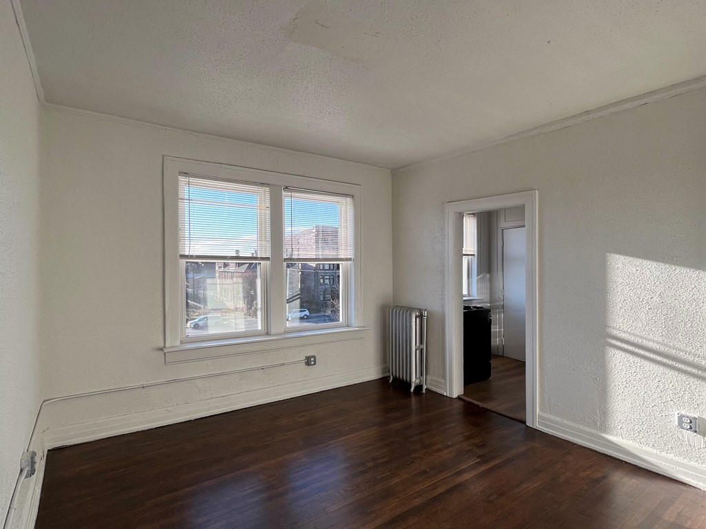 a bedroom with hardwood floors and a large window