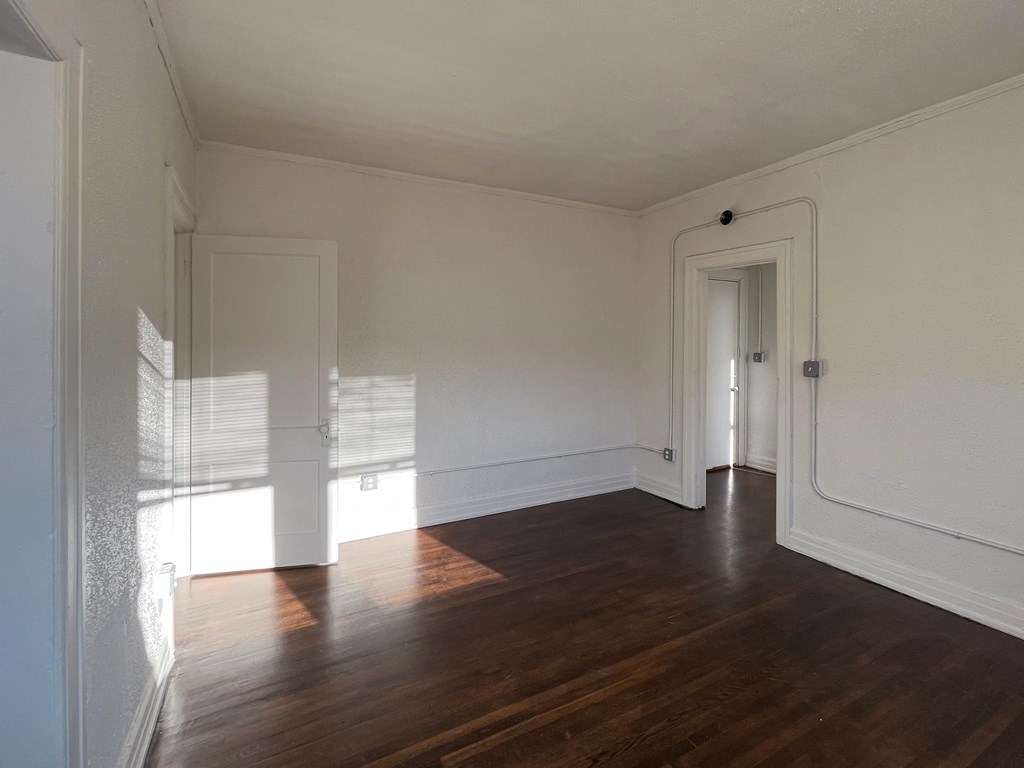 a bedroom with hardwood floors and white walls